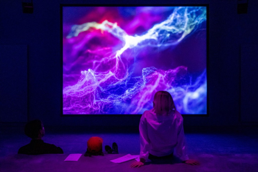 inimene istumas ekraani ees, mille on kujutatud välgulaadseid kujutisi